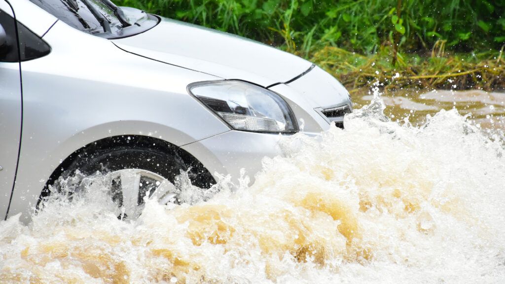 Car driving through deep water during monsoon 2024
